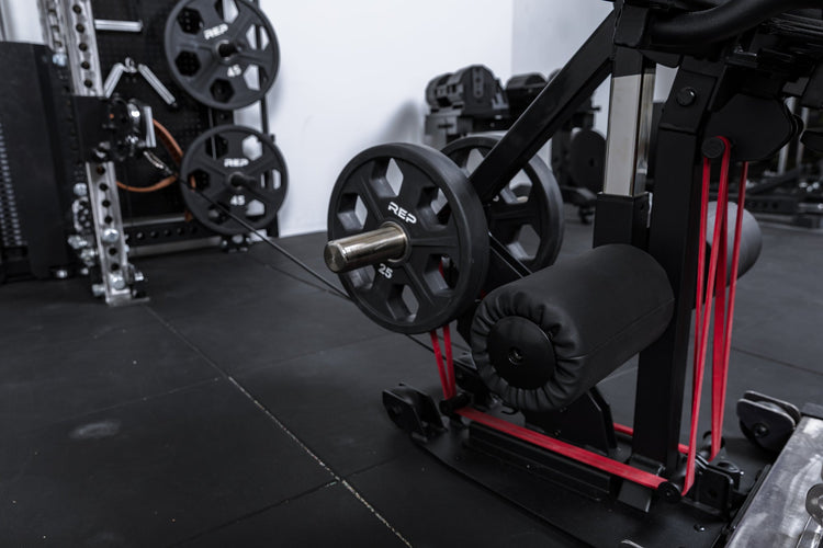 Close-up shot of weight plates, resistance bands, and cable resistance loaded onto the Leg Extension & Leg Curl Bench Attachment