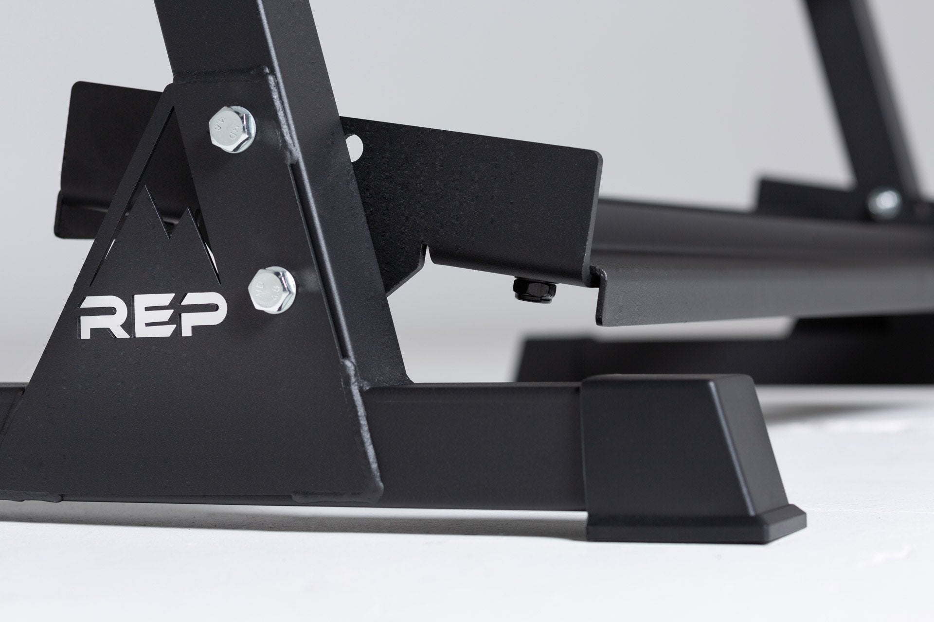 Close-up side view of the bottom of the 3-tiered matte black REP Dumbbell Rack showcasing the